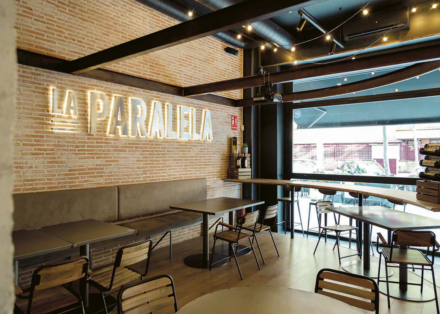 Imagen del interior del restaurante y "La Paralela" en letras de aluminio retroiluminadas mediante luz cálida