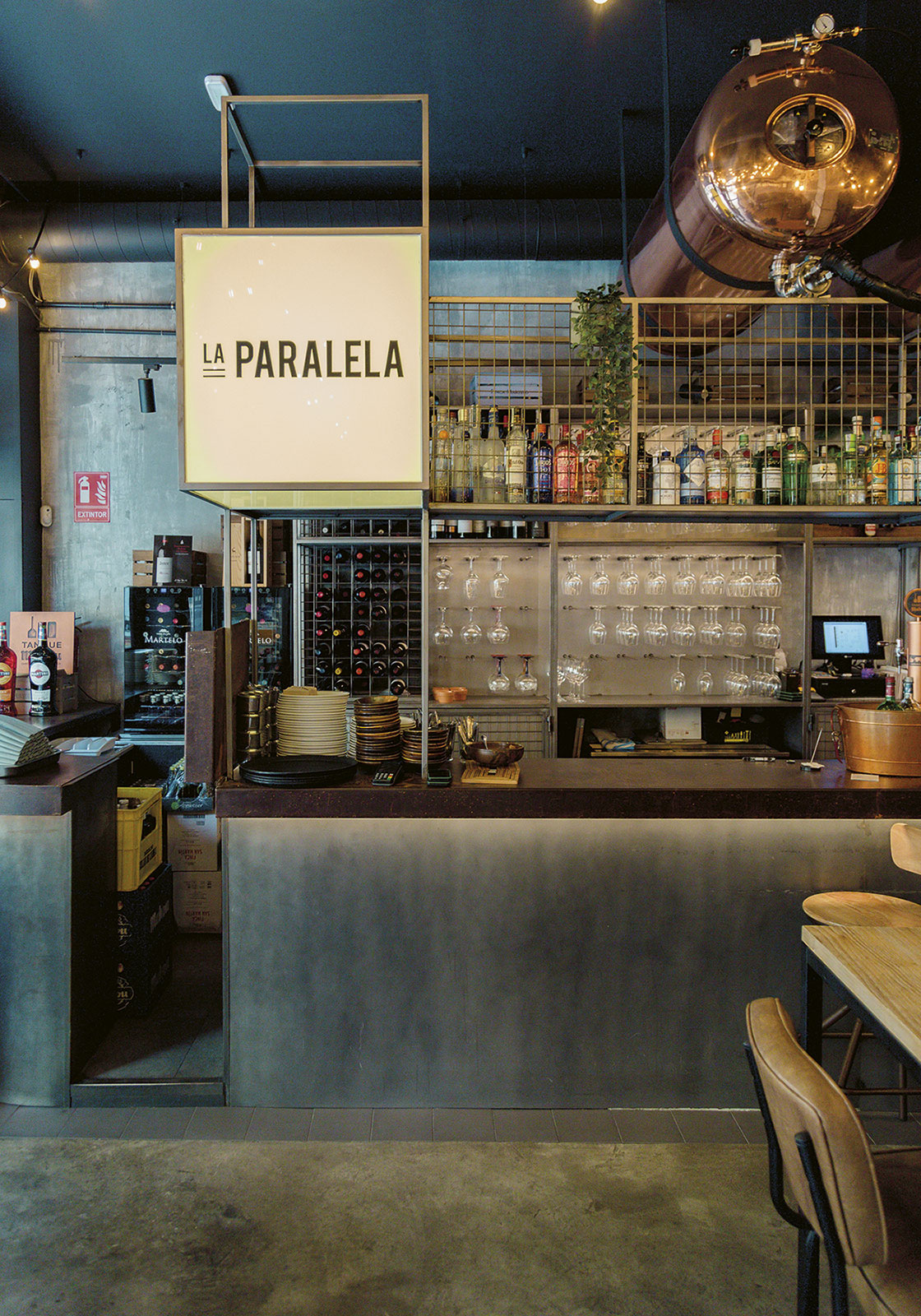 Imagen de la barra del restaurante "La Paralela" y el cubo de metacrilato con planchas adhesivadas con letras de hierro